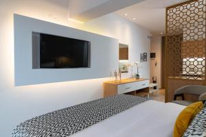 een slaapkamer met een bed en een televisie aan de muur bij F & B Collection - Seaview MiniLux in Thessaloniki