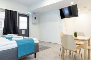 a room with two beds and a table and a television at Oma Hotelli in Ylöjärvi