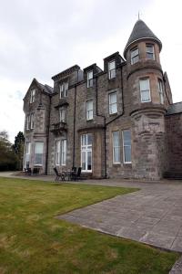 a large brick building with a clock tower at 4 Lomond Castle in Balloch