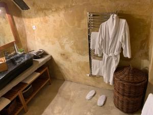 ein Badezimmer mit einem Waschbecken und einem Bademantel, der auf einem Kleiderständer hängt in der Unterkunft Bergerie Truphemus de Savoillan in Savoillan