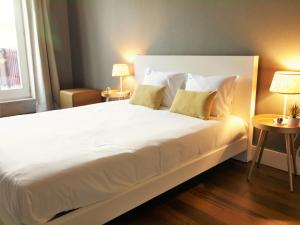 uma grande cama branca num quarto com 2 candeeiros em ALIADOS by YoursPorto em Porto