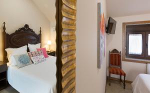 ポイオにあるCasa A Marchantaの白いベッド1台(木製ヘッドボード付)が備わるベッドルーム1室が備わります。
