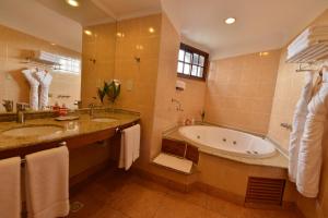 a bathroom with a tub and a sink and a bath tub at Hotel Saint George in Puerto Iguazú