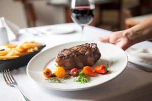 a plate of steak and french fries and a glass of wine at Hotel Saint George in Puerto Iguazú