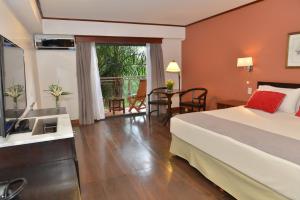 a hotel room with a bed and a television and a table at Hotel Saint George in Puerto Iguazú