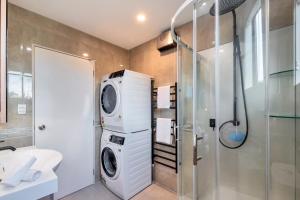 a bathroom with a washing machine and a shower at Greenwich Townhouse with Parking and Air-Con in Auckland +19 photos