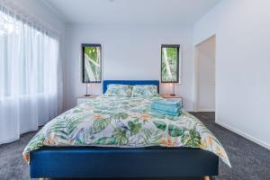 um quarto com uma cama azul e 2 janelas em Hillside Haven - Airlie Beach em Airlie Beach