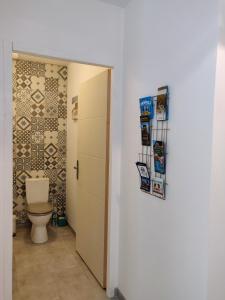 a bathroom with a toilet next to a door at La Maison de Nini in Andernos-les-Bains