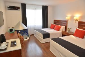 a hotel room with two beds and a window at Hotel Saint George in Puerto Iguazú