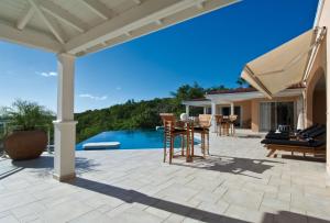 un patio con mesa, sillas y piscina en Dream Villa Terres Basses 543, en Les Terres Basses