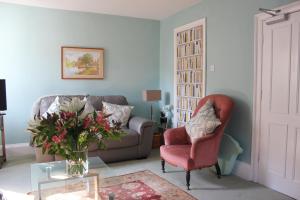 a living room with a couch and a chair and a vase of flowers at Cherubs Nest in Dartmouth