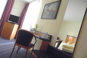 a hotel room with a desk and a mirror at Hotel Alber in Leinfelden-Echterdingen