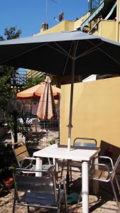 een witte tafel en stoelen met een parasol bij Solimarina in Alghero