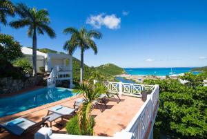 a view of the pool and ocean from the balcony of a house at Dream Villa Anse Marcel 546 in Anse Marcel 