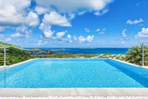 a swimming pool with a view of the ocean at Dream Villa Orient Bay 566 in Orient Bay