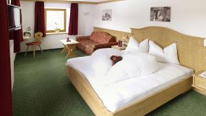um quarto com uma cama grande com travesseiros brancos em Hotel Trenker em Braies