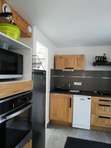eine Küche mit Holzschränken und einer schwarzen Mikrowelle in der Unterkunft Les vacances aux Pouldu in Clohars-Carnoët