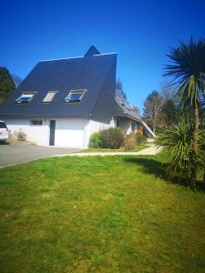 ein weißes Haus mit einem schwarzen Dach und einer Palme in der Unterkunft Joelle et Hans B&B in Hôpital-Camfrout