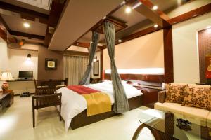 een slaapkamer met een hemelbed en een bank bij Hotel Bintang Pari Resort (Adult Only) in Kobe