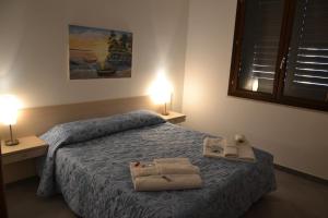 a bedroom with two towels on a bed with two lamps at Case Vacanza Torre Lupa in Marsala