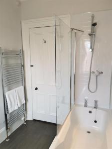 baño blanco con ducha y puerta de cristal en No 48 Castle View, en Inverness
