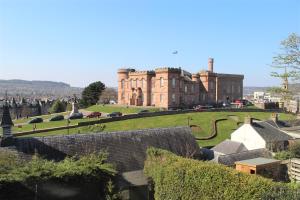 an old castle with a large building in the background at No 48 Castle View in Inverness