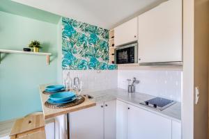 a kitchen with white cabinets and blue plates on a counter at HONORÊ - Suite Carnot in Lyon