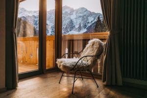 a chair on a balcony with a view of mountains at Boutique hotel Vila Planinka in Zgornje Jezersko