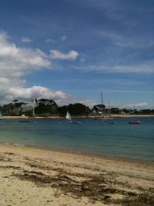 a beach with boats in the water on a cloudy day at Les jardins du vivier in Combrit