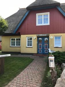 a red and yellow house with a blue door at "Bootsmannskammer" by Ferienhaus Strandgut in Born