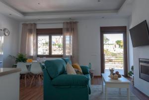 a living room with a green couch and a table at Apartamentos Cantarería, Jazmín. in Setenil