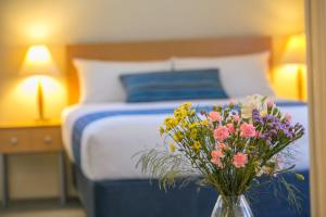 a bedroom with a bed with a vase of flowers on a table at Amalfi Resort in Busselton
