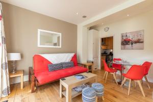 ロンドンにあるBright Clapham flat with private garden, sleeps 4のリビングルーム(赤いソファ、テーブル付)