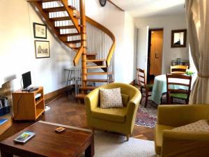 ein Wohnzimmer mit einer Treppe, Stühlen und einem Tisch in der Unterkunft Le Penthouse Thorigny in Paris