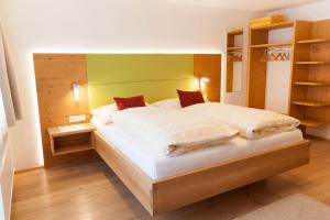 a bedroom with a large bed with a wooden headboard at B&B Landhaus Vierthaler in Filzmoos