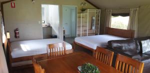 Cette chambre comprend deux lits, une table et un canapé. dans l'établissement Southern Sky Glamping, à Mount Tamborine