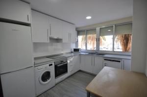 una cucina con armadi bianchi e una lavatrice/asciugatrice di Apartamento Frente Al Mar a Valencia
