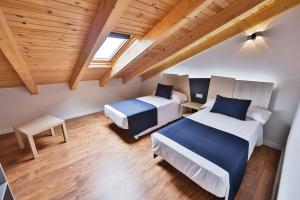 two beds in a room with wooden ceilings at Apartamentos Playa de Camariñas in Camariñas