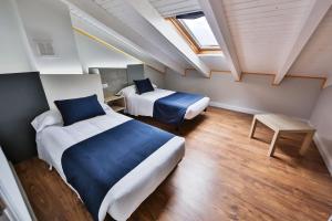 Un dormitorio con dos camas y una claraboya. en Apartamentos Playa de Camariñas, en Camariñas