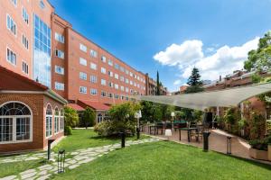 un patio con mesas y sillas frente a un edificio en Rafaelhoteles Atocha en Madrid