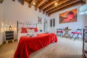sypialnia z łóżkiem z czerwonym kocem i stołem w obiekcie Apartamentos Jerez w mieście Jerez de la Frontera