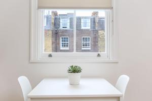 ロンドンにあるKings Cross Serviced Apartments by Concept Apartmentsの窓際の白いテーブルと椅子