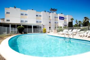 a swimming pool in front of a hotel at Kyriad Toulon Est Hyeres La Garde in La Garde