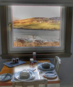 a table with a view of the water from a window at Old Nurses Cottage in Skeabost