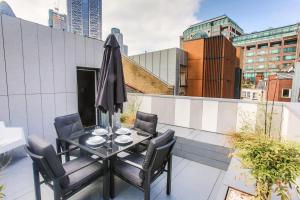 Un balcón con una mesa y sillas y una sombrilla. en Room Home Stay, en Londres