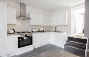 La cuisine est équipée de placards blancs et d'un four avec plaques de cuisson. dans l'établissement The Marylebone Residence, à Londres