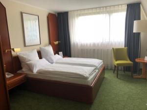 a hotel room with a bed, chair, and nightstand at Hotel Engel in Bad Kreuznach