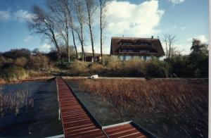 une maison sur un lac avec un quai en bois dans l'établissement Der Fuchsbau, à Meesiger