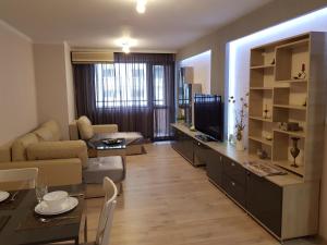 a living room with a couch and a table with a television at Хепи Апартмънтс in Plovdiv