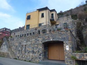un bâtiment au sommet d'un mur en pierre avec une porte dans l'établissement Riomaggiore SeaView, à Riomaggiore